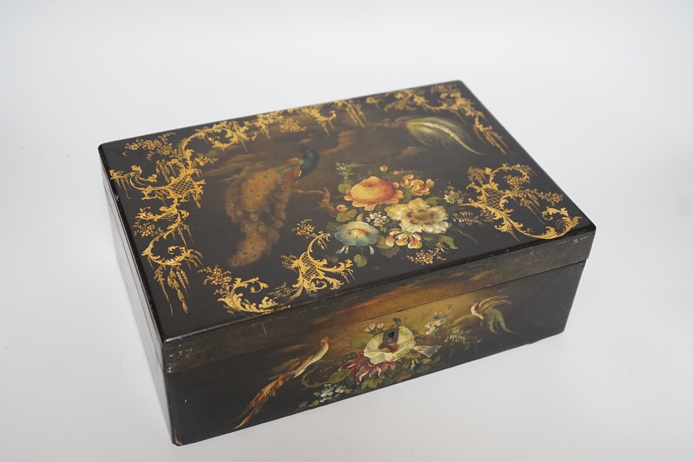 A Victorian painted papier-mâché sewing box, with peacock, blossom and gilt decoration with wooden inset, 30cms wide x 11cms high